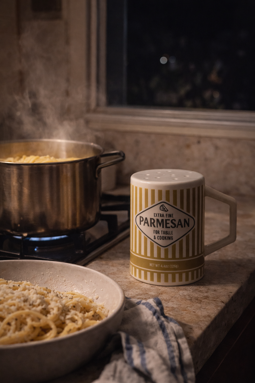 Parmsasen cheese shaker next to a pot of pasta on a stove