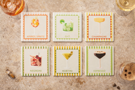 Set of six cocktail-themed coasters on a textured surface with drinks around them. Cocktail coasters 