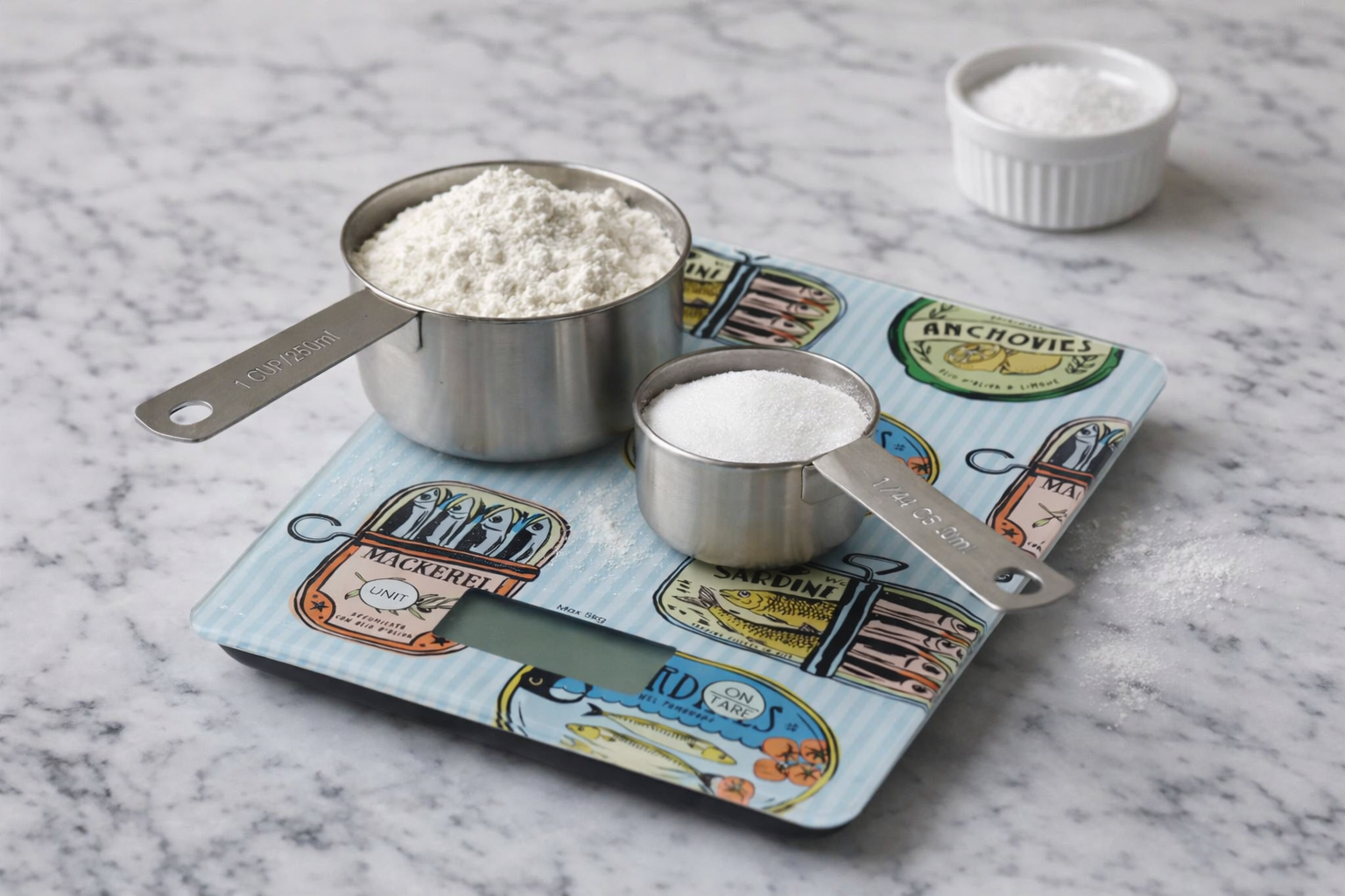 Measuring cups with flour and sugar on a decorative kitchen scale with a marble background
